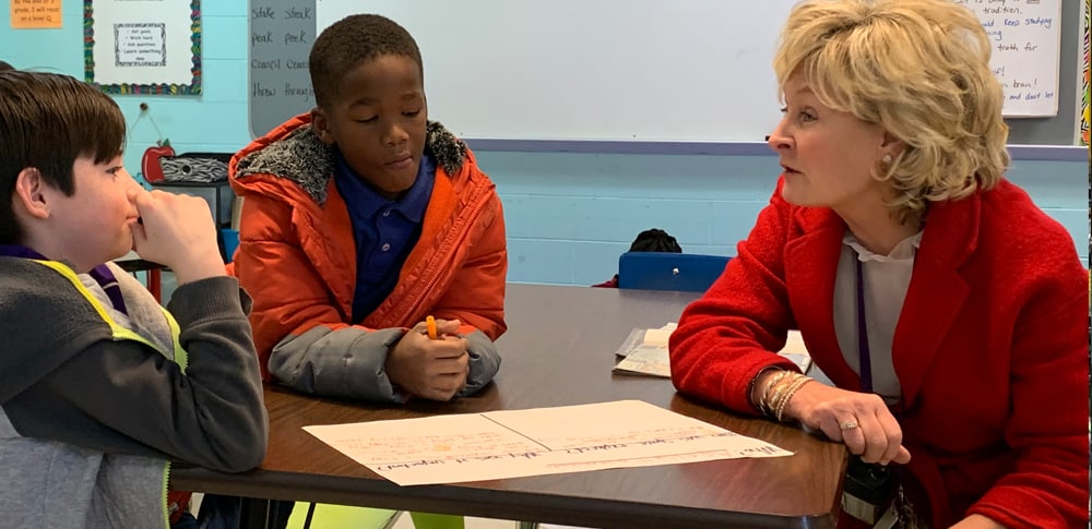 A teacher works with students at a table